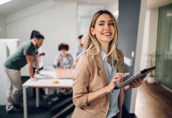 Mujer sonriendo con ipad a la derecha de la foto